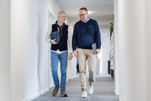 Marc Ellinghaus und Christian Buß laufen nebeneinander durch den Flur und besprechen sich