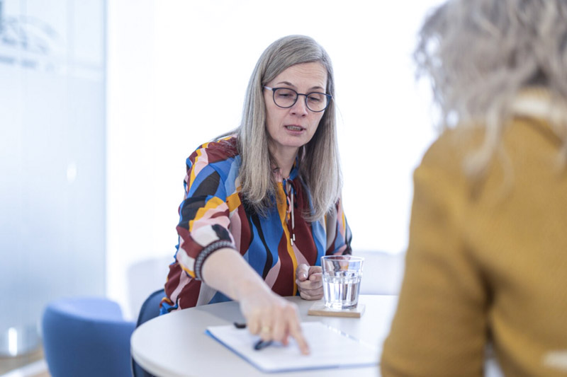 Nicole Buß und eine Mandantin sitzen an einem Tisch und besprechen sich